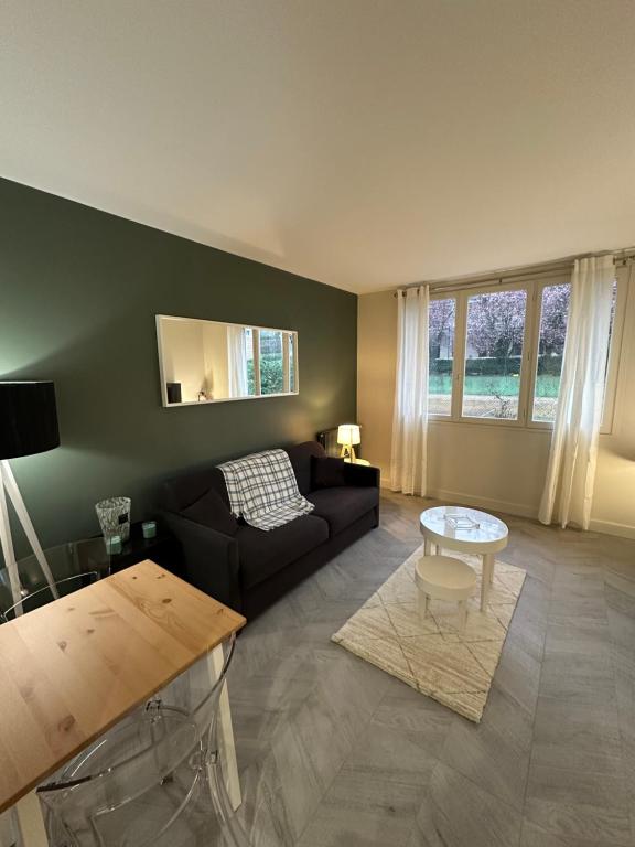 a living room with a couch and a table at Studio Villennes sur seine cosy Paris Versailles in Villennes-sur-Seine
