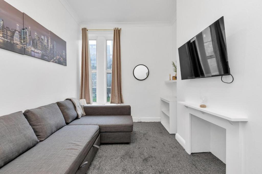 uma sala de estar com um sofá e uma televisão em The Brixton Inn em Londres