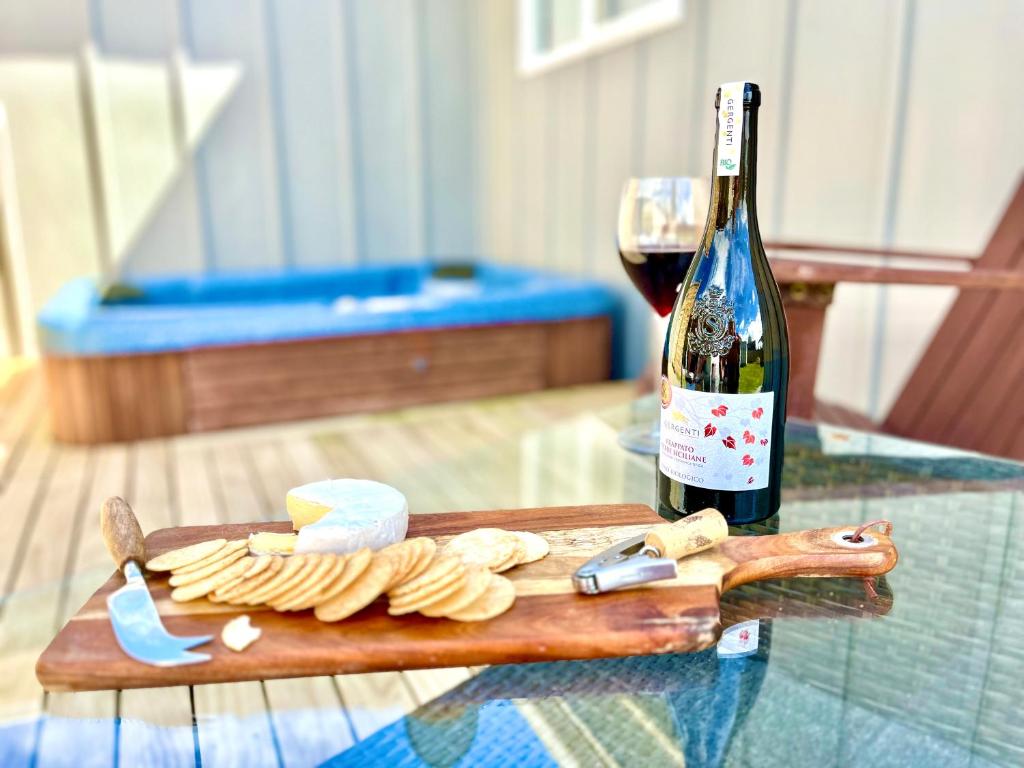 una botella de vino y una tabla de cortar de madera con queso en Lake life with a hot tub, en Mangakino