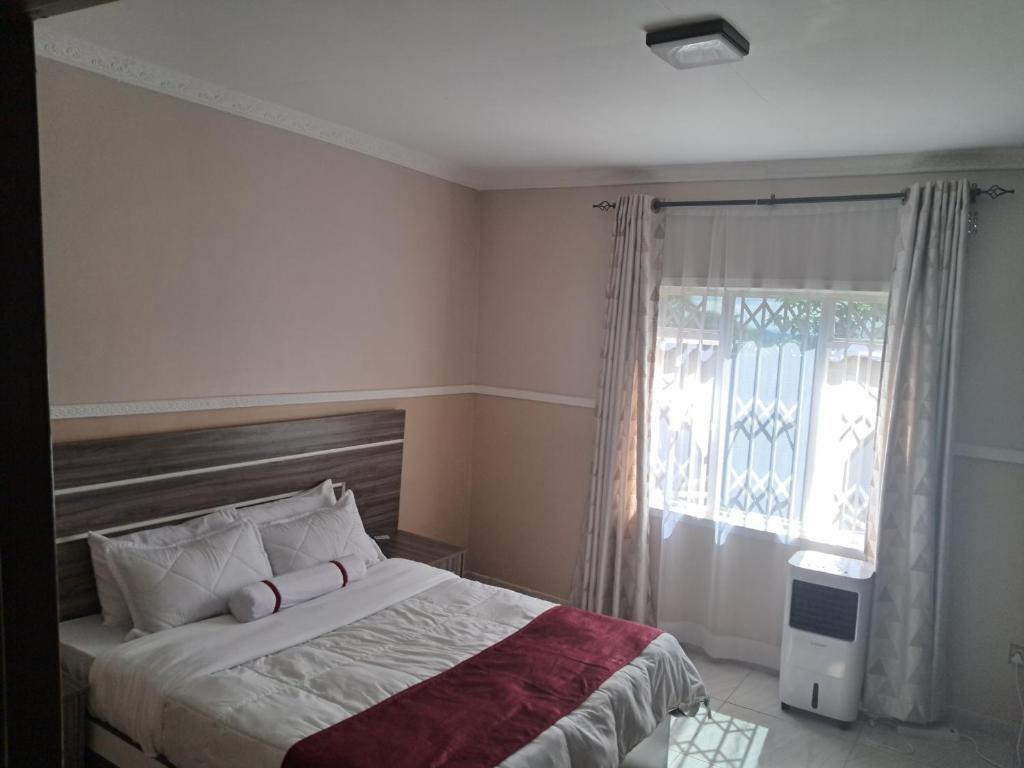 a bedroom with a large bed and a window at Nkolokosa BnB in Blantyre