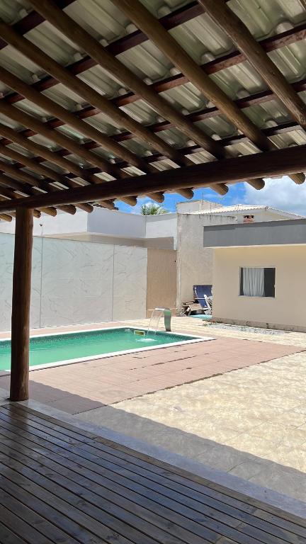a swimming pool with a wooden pergola next to a house at Casa Paraiso de Praia in Porto Seguro