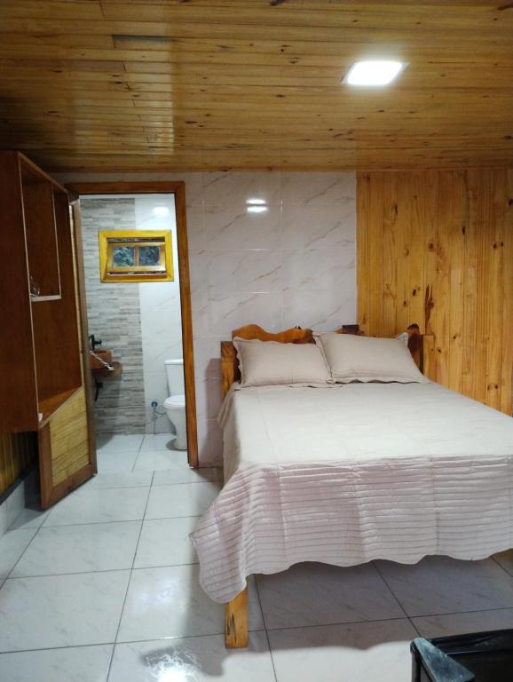 a bedroom with a large bed and a bathroom at Hotel Fazenda Rancho Grande in Linha Blinda