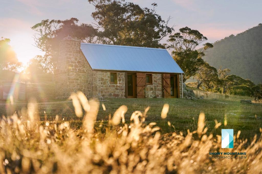 ein Steinhaus mit blauem Dach auf einem Feld in der Unterkunft The Stone Cottage at Wollondibby - Heritage Listed l Renovated l Fire Place in Crackenback