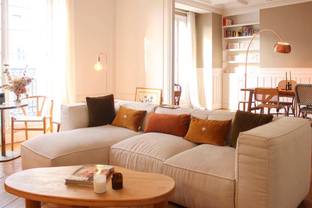 een woonkamer met een witte bank en een tafel bij Spacious haussmann apartment in Parijs