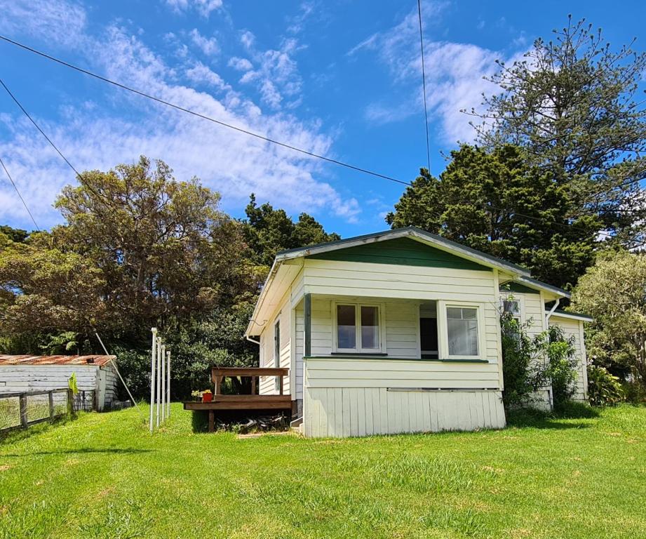 a small white house in a grassy yard at Truffle Honey Cottage in Warkworth