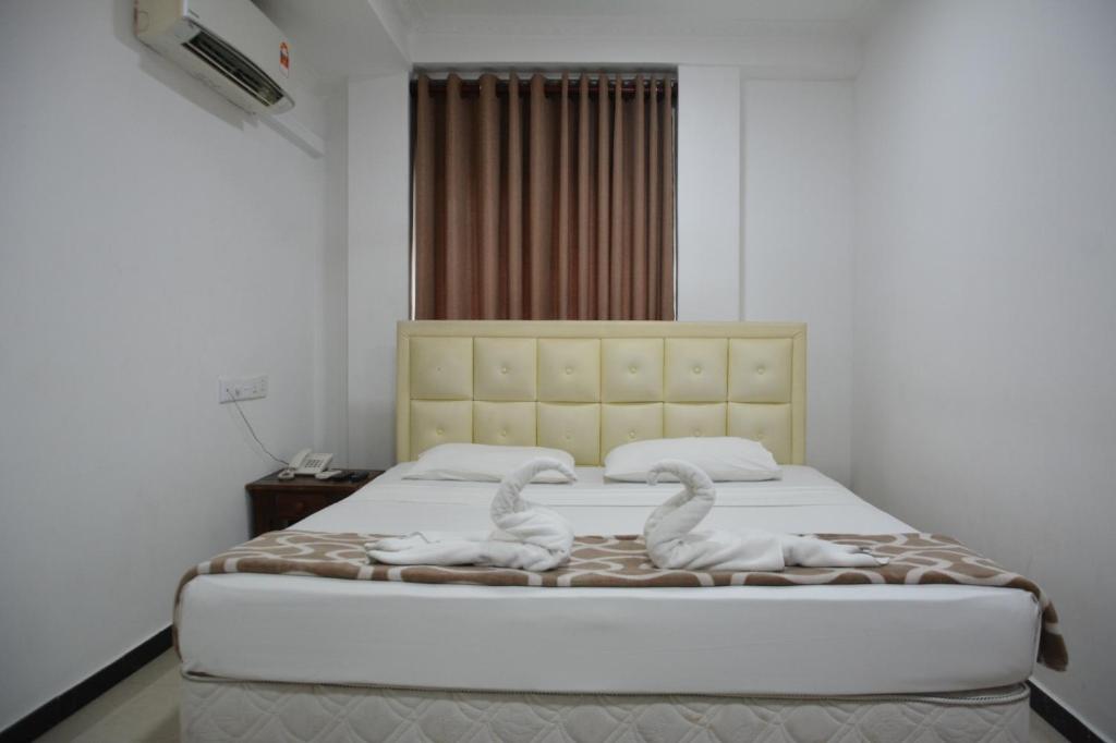 two swans sitting on a bed in a bedroom at Saasha City Hotel in Colombo