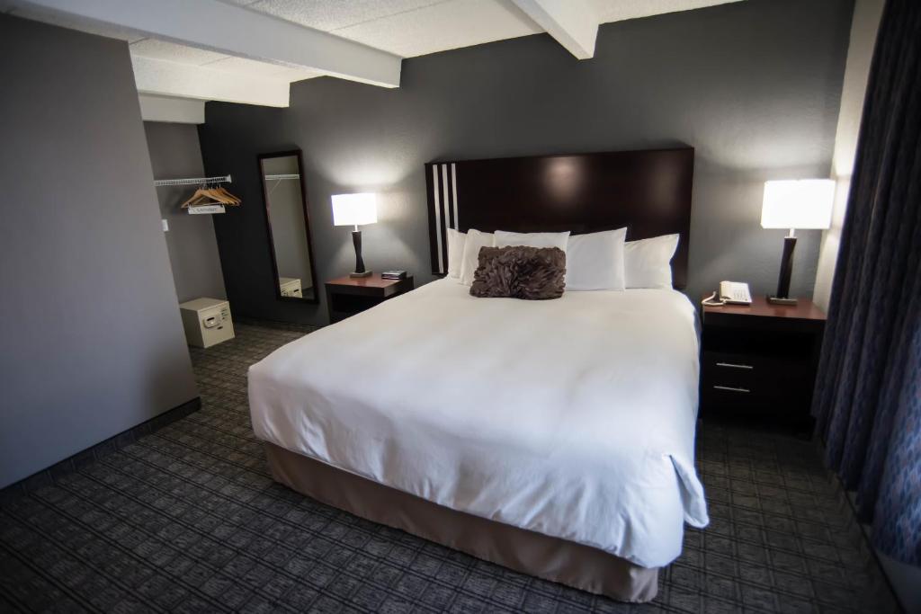 Eastland Suites Extended Stay Hotel & Conference Center Urbana في شامبين: سرير كبير في غرفة الفندق مع مصباحين