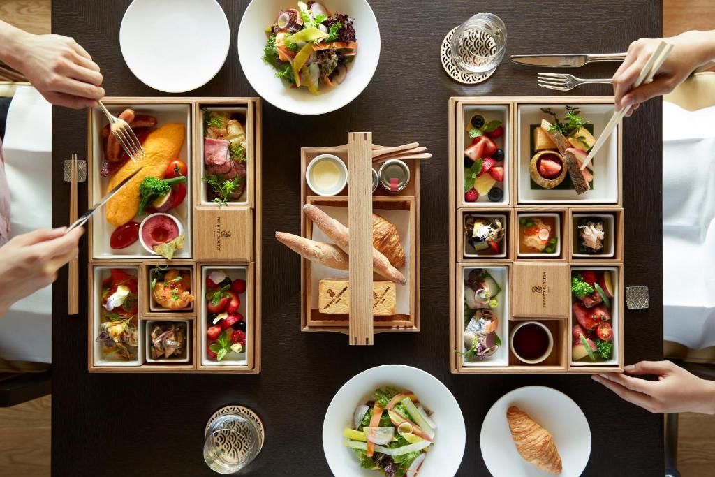 ein Tisch voller Teller mit Speisen, die die Leute essen in der Unterkunft The Ritz-Carlton, Nikko in Nikko
