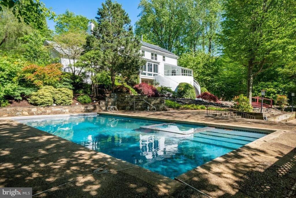 a swimming pool in front of a house at Tara Retreat: Family-Friendly Oasis with Pool, Tennis & Serene Ambiance in Potomac in Potomac