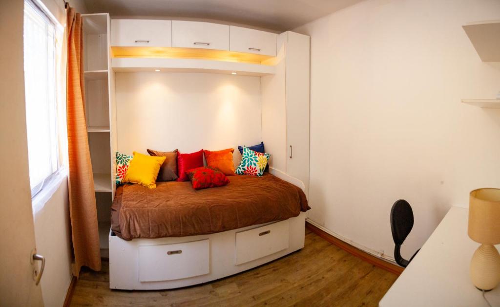 a bedroom with a bed with colorful pillows on it at COZY POCKET SIZE SWEET DEAL in Santiago
