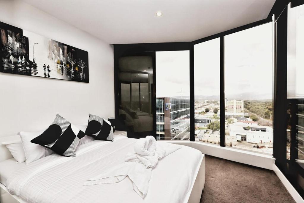 białe łóżko w pokoju z dużymi oknami w obiekcie Iconic on Vue with Free Parking Pool Gym CBD w mieście Adelaide