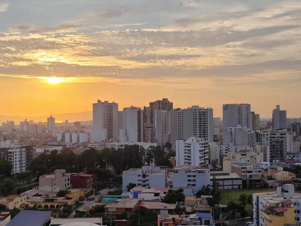 a city skyline with the sun setting behind buildings at Hermoso apartamento Unidos En Familia en JESÚS MARÍA in Lima
