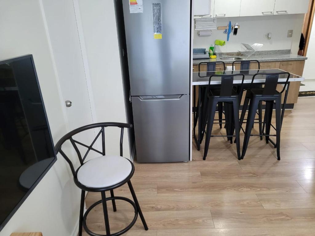 Il comprend une cuisine équipée d'une table, de chaises et d'un réfrigérateur. dans l'établissement Departamento Brisa del sol, à Talcahuano