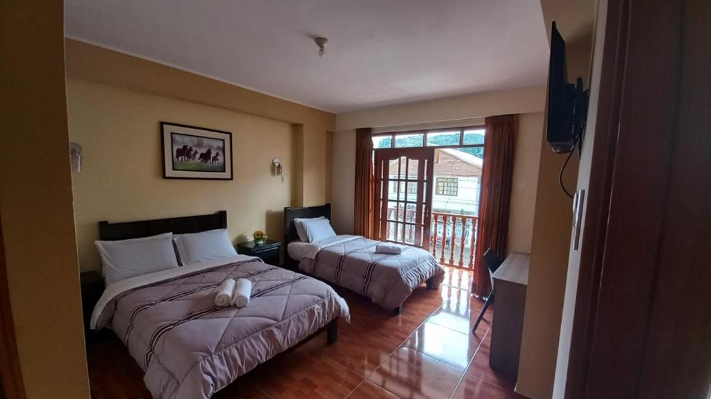a hotel room with two beds and a television at Hospedaje "LOS QUETZALES DE OXAPAMPA" in Oxapampa