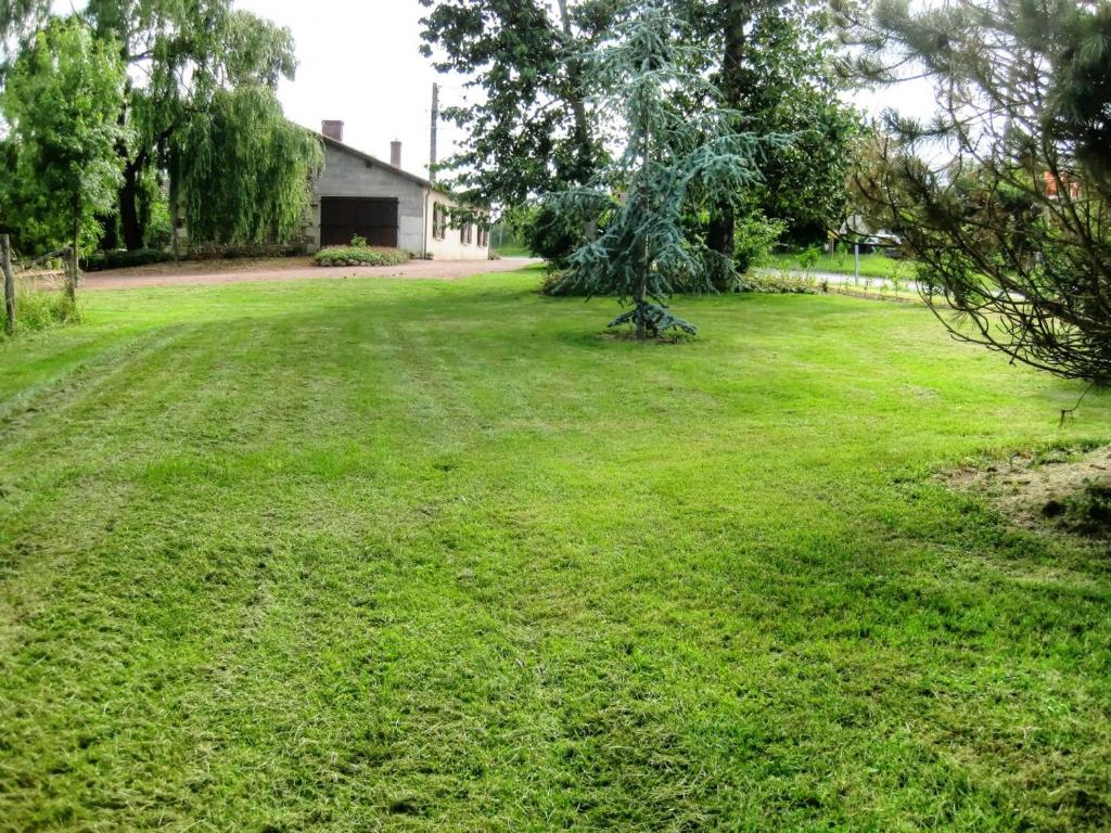 a large grassy yard with a tree in the middle at Gîte familial en Touraine avec jardin, proche châteaux et vignobles, animaux acceptés. - FR-1-381-240 in Mazières-de-Touraine