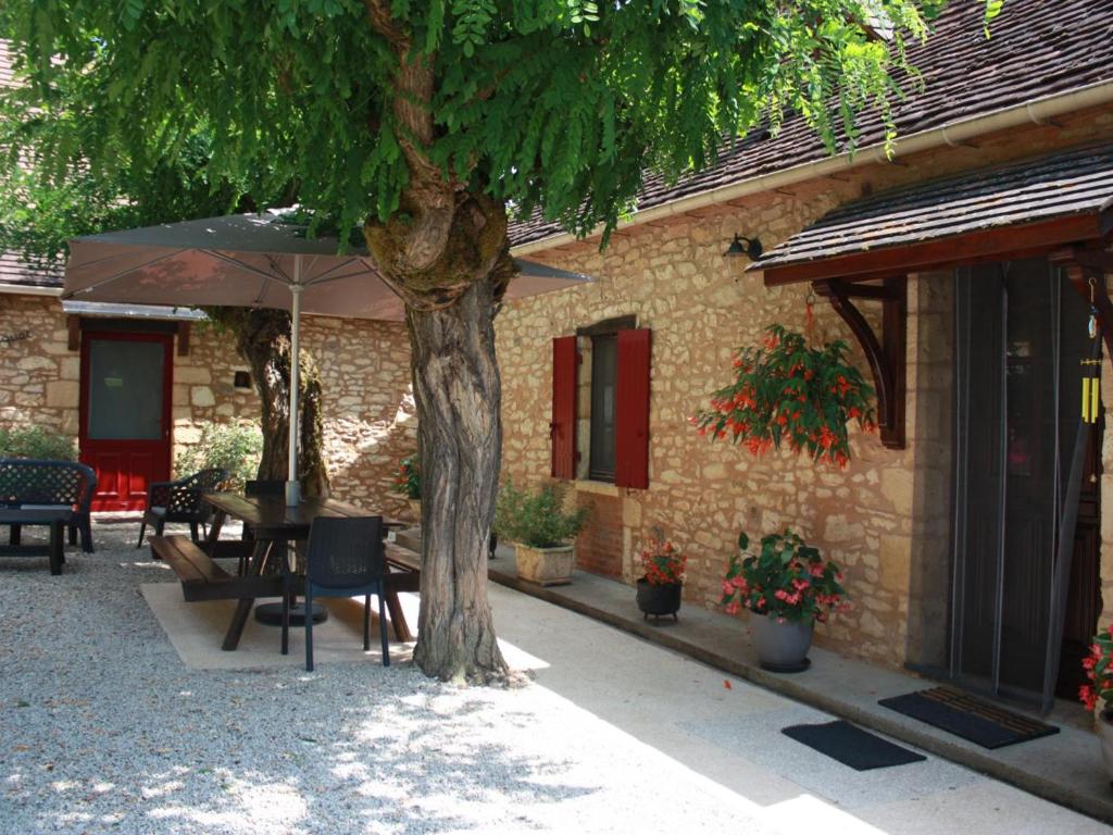 a table and chairs under an umbrella next to a building at Maison de caractère avec jardin, proche rivière, équipements enfants, à 3 km du Bugue - FR-1-616-176 in Limeuil