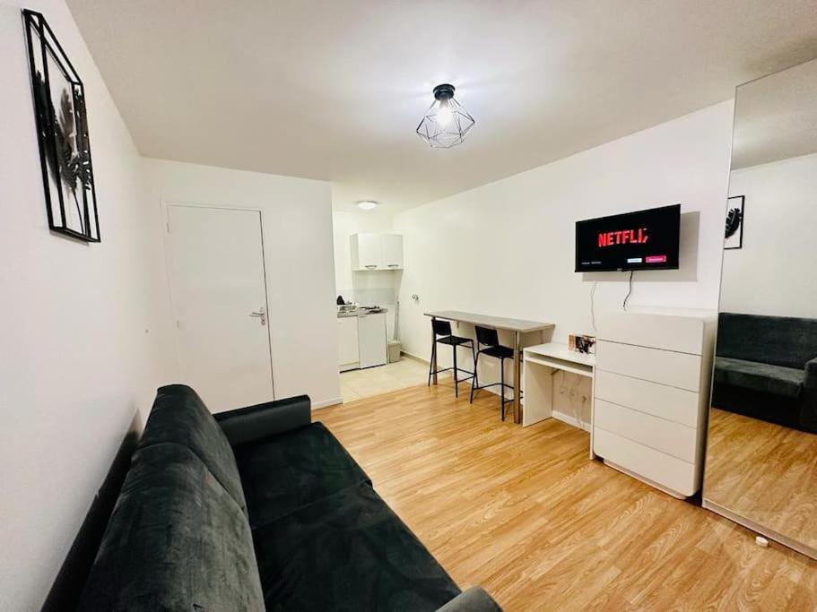 un salon avec un canapé et une horloge au mur dans l'établissement Superbe studio proche du Casino/Stade de France, à Soisy-sous-Montmorency