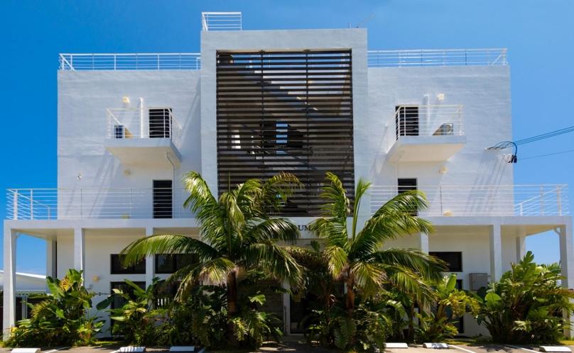 a white building with palm trees in front of it at CASA DUMAI OceanVilla NAKIJIN in Nakijin
