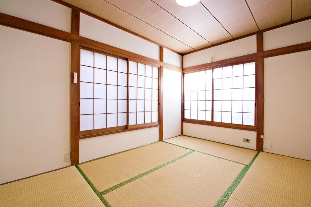 una habitación vacía con dos ventanas en un edificio en 梅屋敷貸戸建, en Tokio