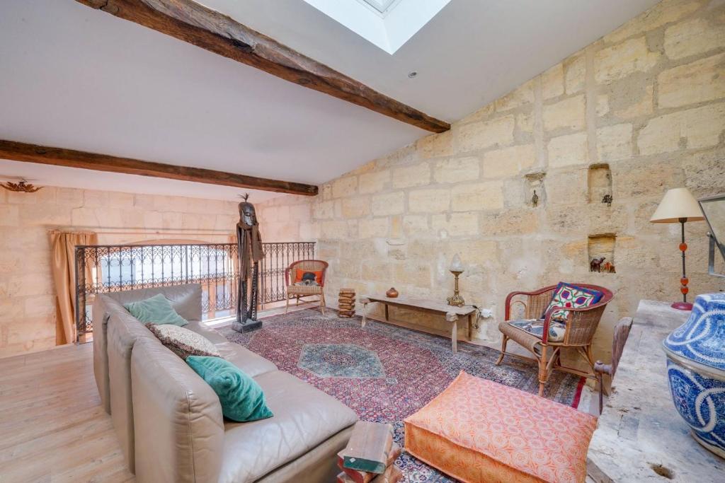 sala de estar con sofá y pared de piedra en Very charming apartment Bordeaux Chartrons, en Burdeos