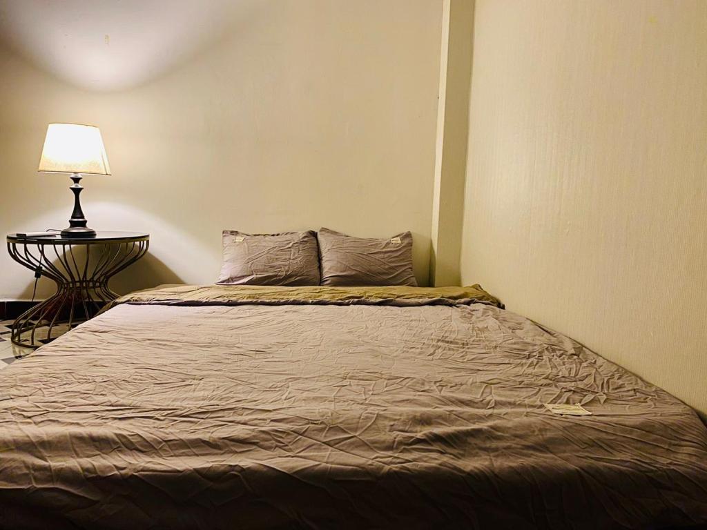 a bed in a bedroom with a lamp on a table at SÀI GÒN INN ĐỀ THÁM in Ho Chi Minh City