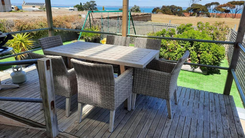 a wooden table and chairs on a deck with the beach at Kangaroo Island Accommodation in Kingscote