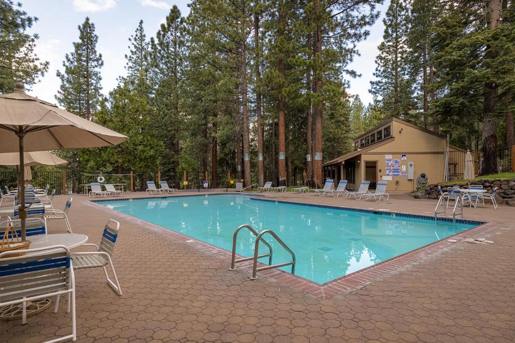 a large swimming pool with chairs and an umbrella at Rooted Resort in Kings Beach