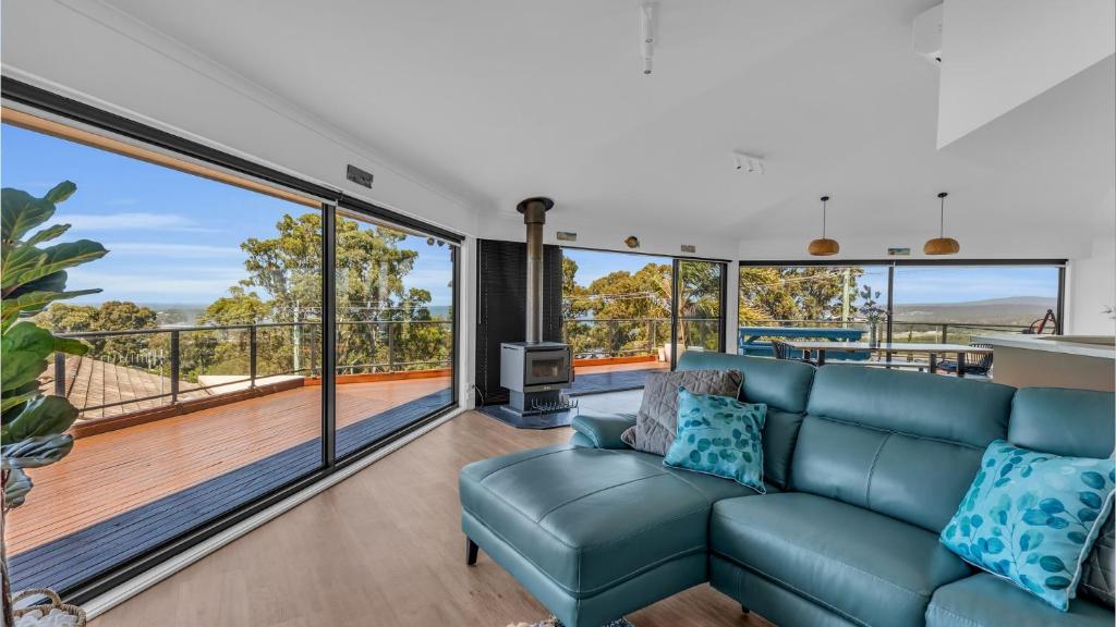 a living room with a blue couch and large windows at Merimbula Heights in Merimbula
