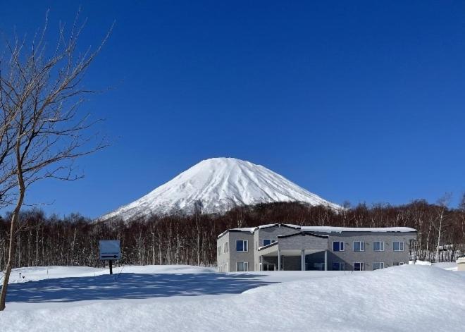 a snow covered mountain behind a building in front of a building at ゲストハウス ikoi in Kyōgoku