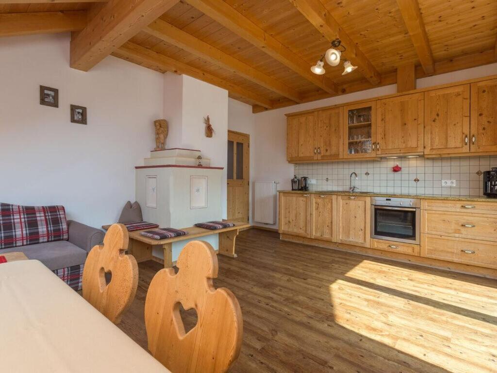 eine große Küche mit Holzschränken und einem Tisch in der Unterkunft Cosy apartment in Welsberg in Welsberg-Taisten