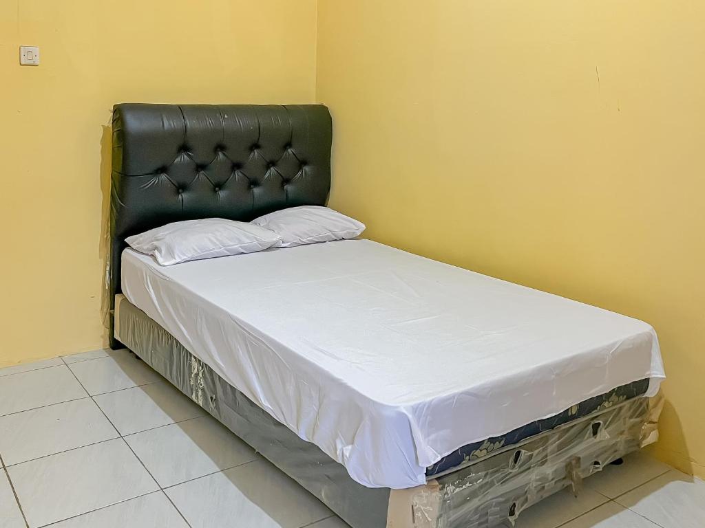a small bed with a black headboard in a room at Penginapan Diar near Pantai Santolo RedPartner in Cilauteureun