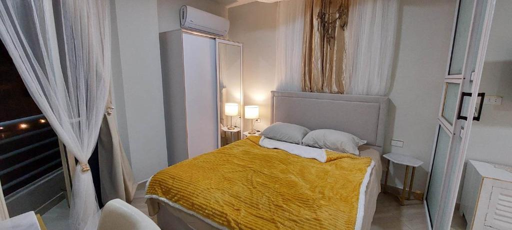 a small bedroom with a bed with a yellow blanket at Apartman Princess 148a in Hurghada