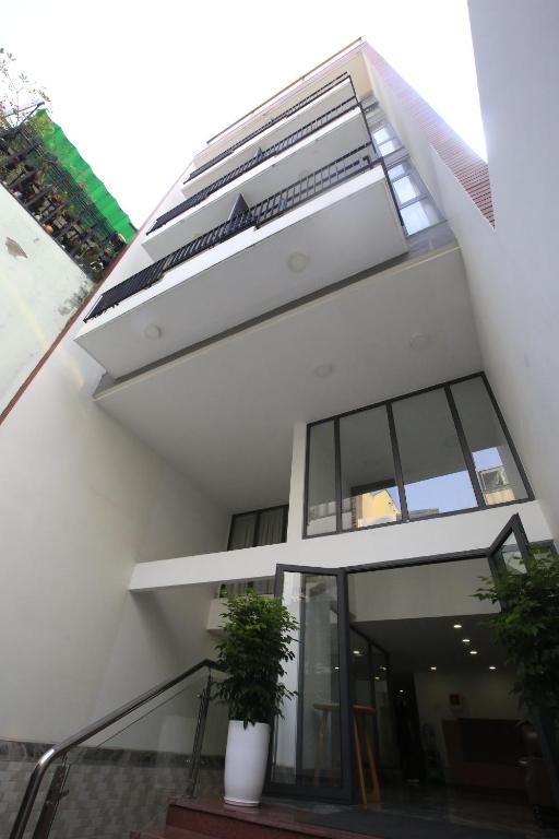 a white building with two potted plants on the stairs at Cityhouse - Nguyễn Đình Chiểu in Ho Chi Minh City