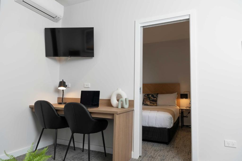 1 dormitorio con escritorio, ordenador y cama en Amica Serviced Apartments en Orange