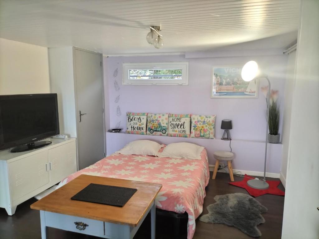 a bedroom with a bed with a table and a tv at Studio très calme 5mn VICHY in Bellerive-sur-Allier