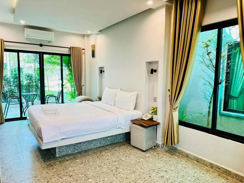 a bedroom with a white bed and a balcony at Raing Phnom Bungalow in Kampot