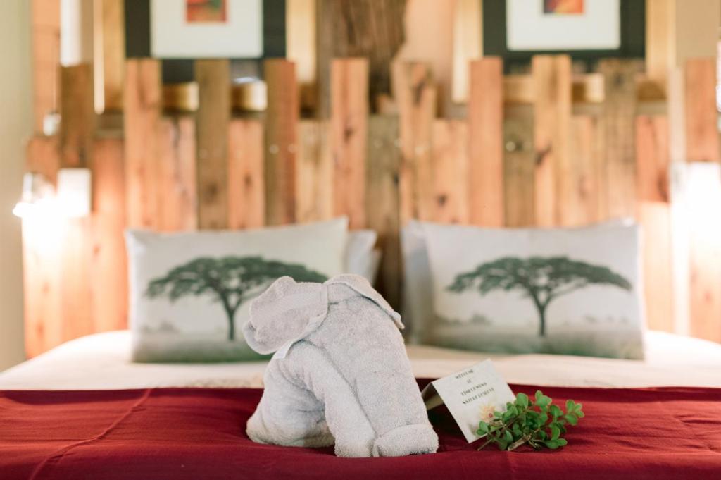 un elefante de peluche sentado en la parte superior de una cama en Limpokwena Nature Reserve, en Tokio