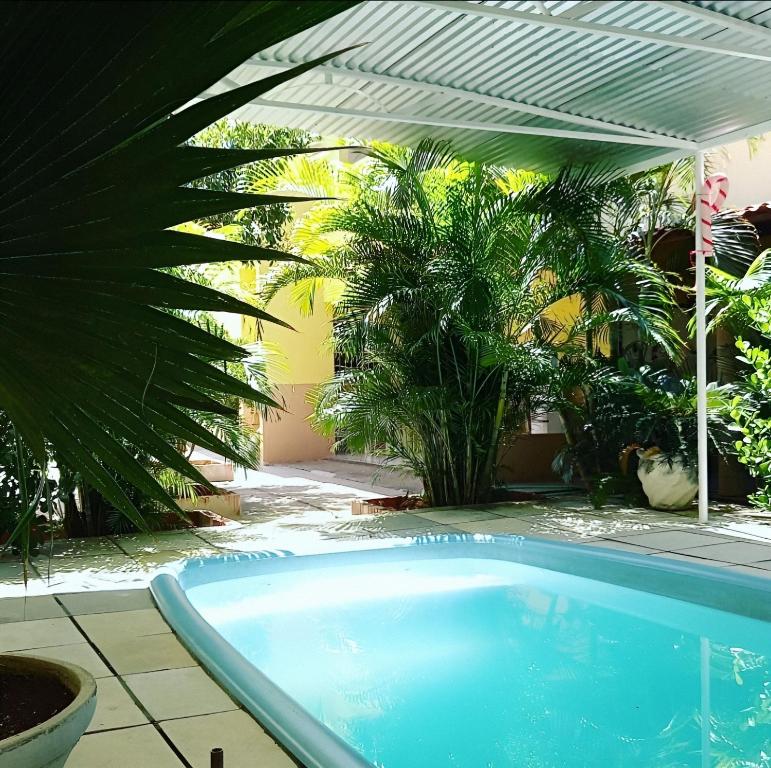 een zwembad in een tuin met een pergola bij Hostel Horizonte Ceará in Horizonte