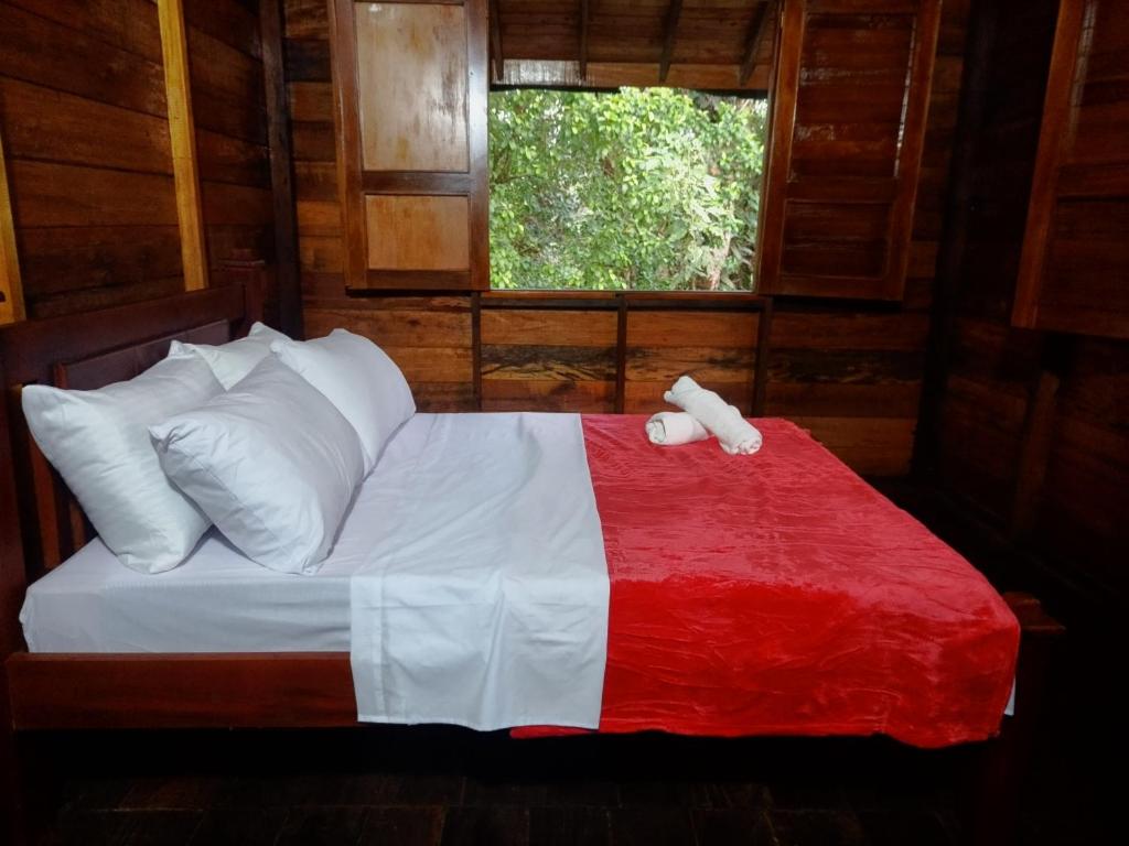 a bedroom with a bed with a red and white blanket at Paraíso Verde Lodge in Quibdó