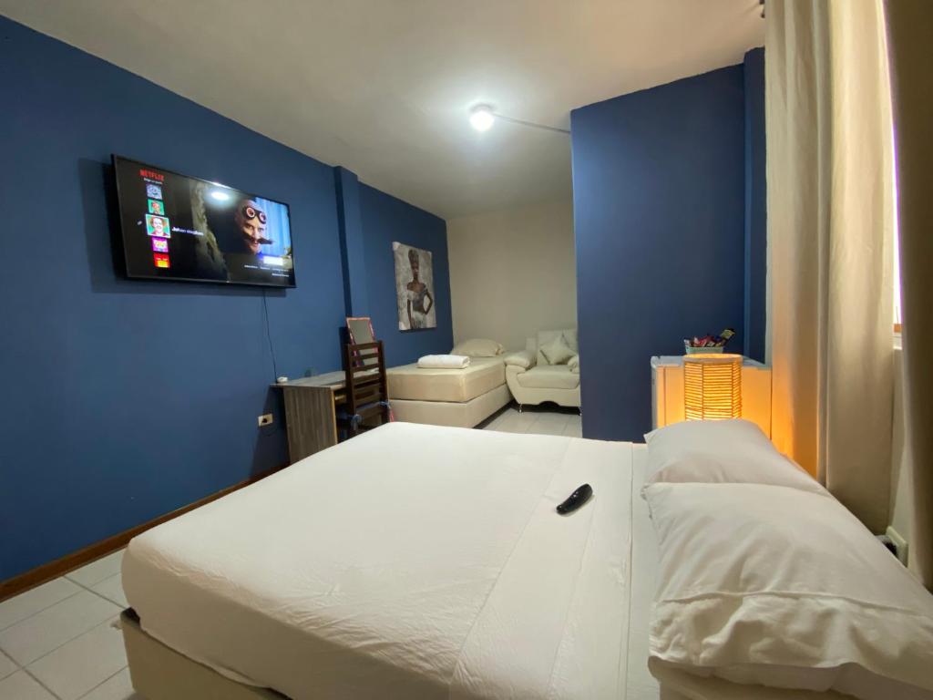 a bedroom with a white bed and a blue wall at Casa Johans in Piura