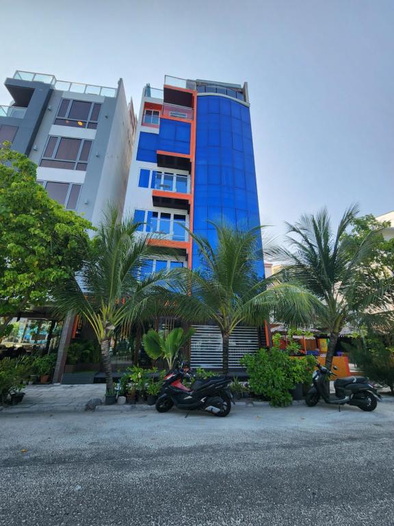 duas motos estacionadas em frente a um edifício com palmeiras em The Hive Beach em Malé