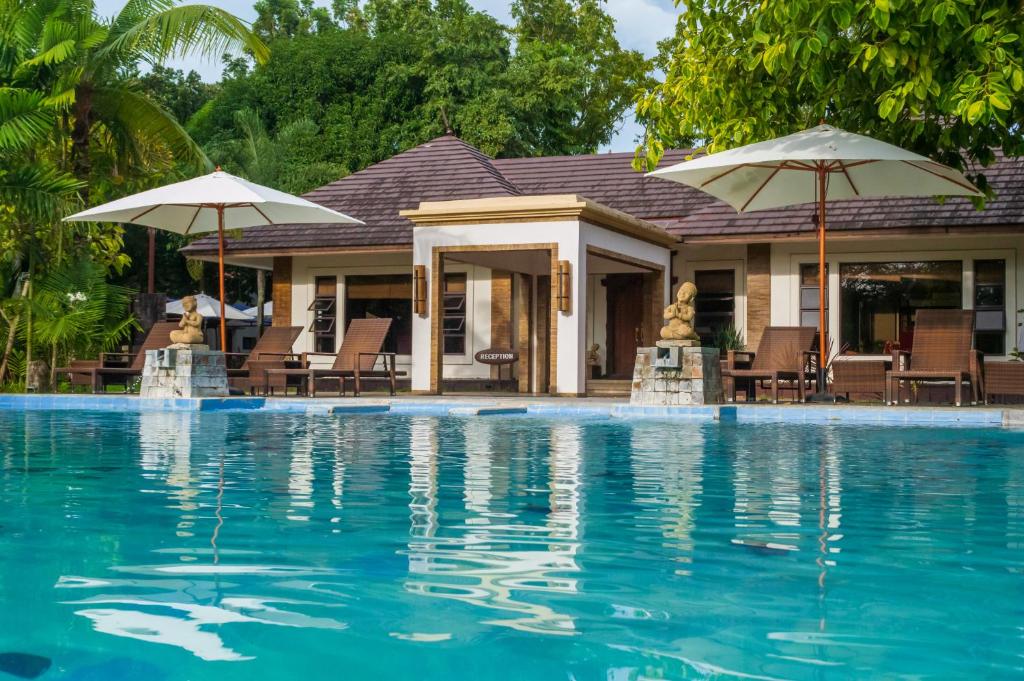 une maison avec une piscine entourée de parasols dans l'établissement Sheridan Boutique Resort Iloilo, à Iloilo
