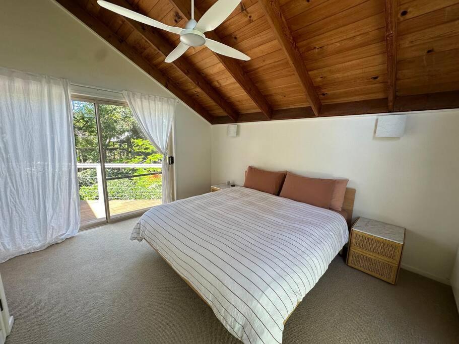 a bedroom with a bed and a ceiling fan at The Tree House Byron Bay in Byron Bay