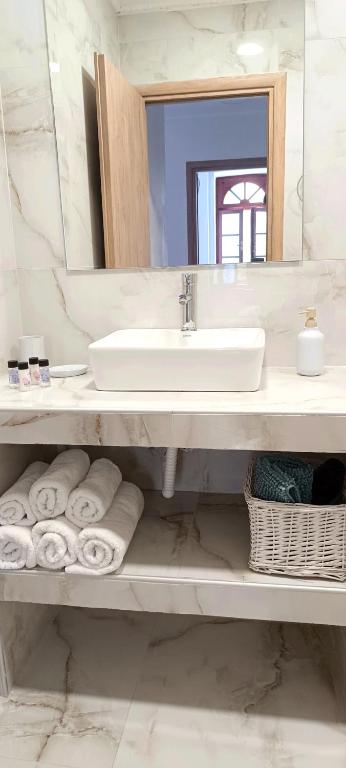 a bathroom with a sink and a mirror and towels at Apeiron Acropolis Suites in Athens