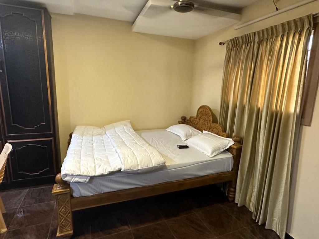 a bedroom with a bed with white sheets and a window at Mookambika tower room in Tiruvannāmalai
