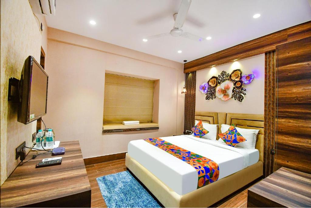 una camera da letto con un grande letto bianco e una televisione di FabHotel Prime Jalsa a Calcutta