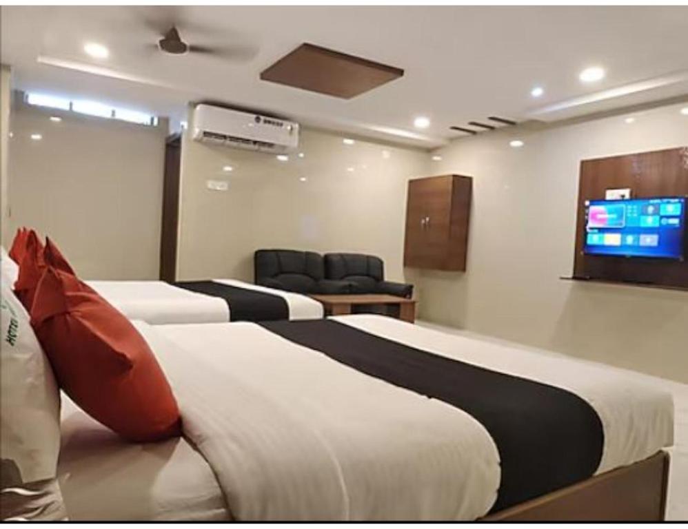 a hotel room with two beds and a flat screen tv at Hotel Grand Inn, Warangal in Warangal