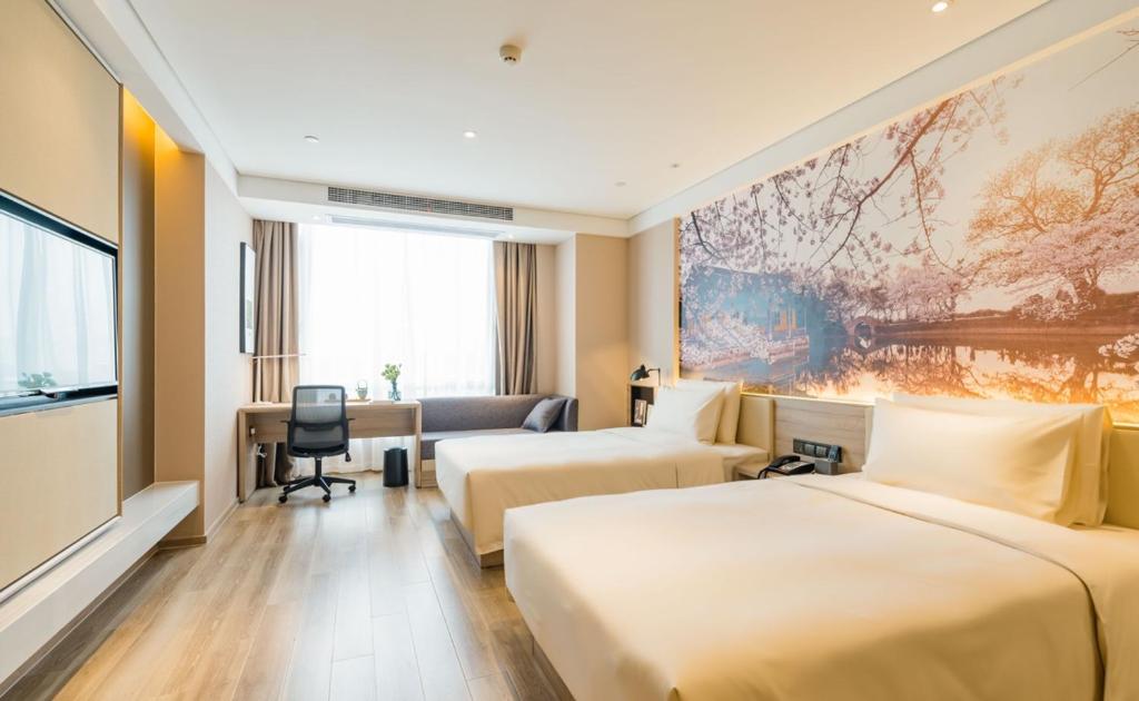 a hotel room with two beds and a desk at Atour Hotel Changjiang North Road Wuxi in Wuxi
