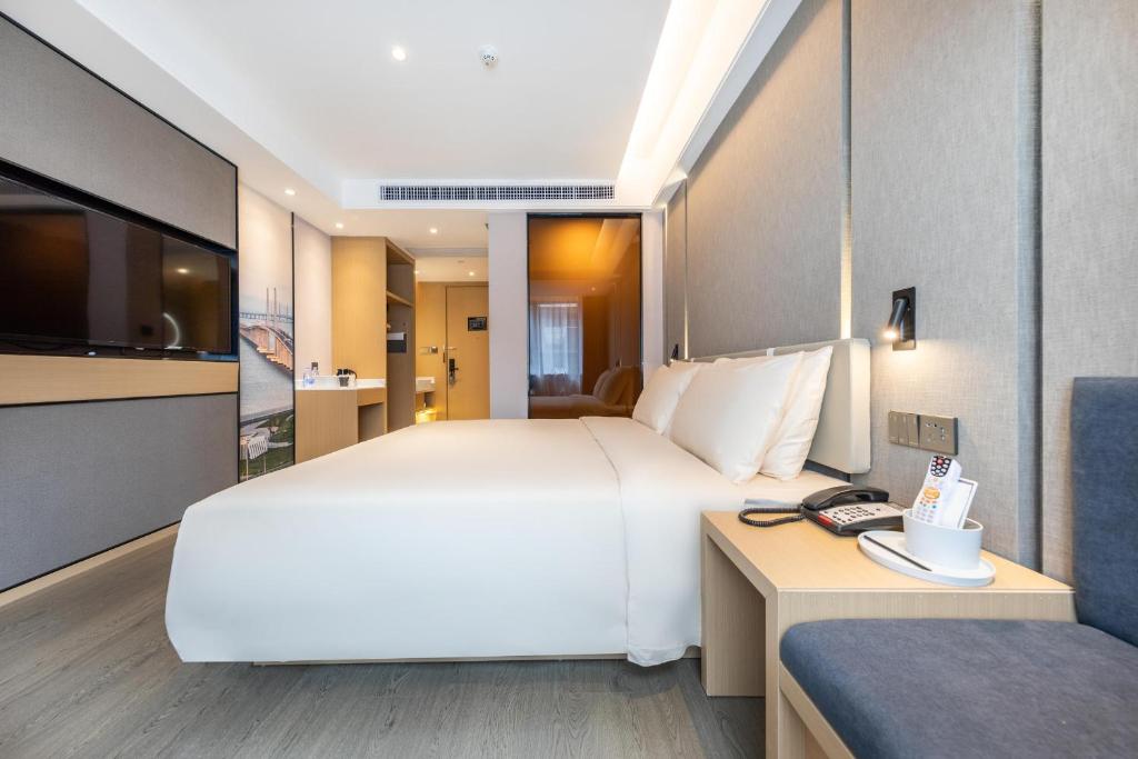 a bedroom with a large white bed and a desk at Atour Light Hotel Zhuhai Lovers Road Grand Theater in Zhuhai