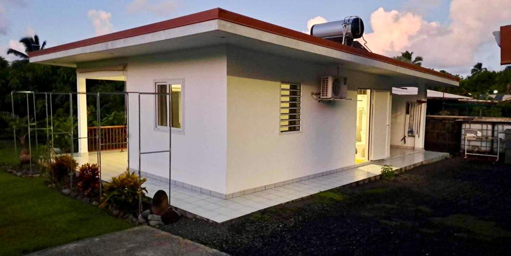 una pequeña casa blanca con techo rojo en ATITAUTU Guest House, en Tautira